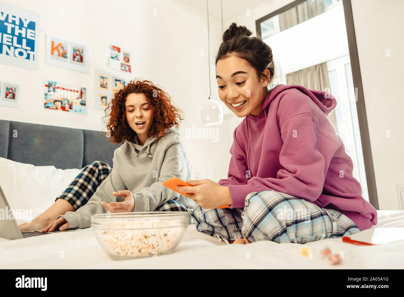 Lächelnden jungen Frauen zusammen auf dem Bett zu sitzen und die Vorbereitung für die Wiedergabe von Filmen Stockfoto