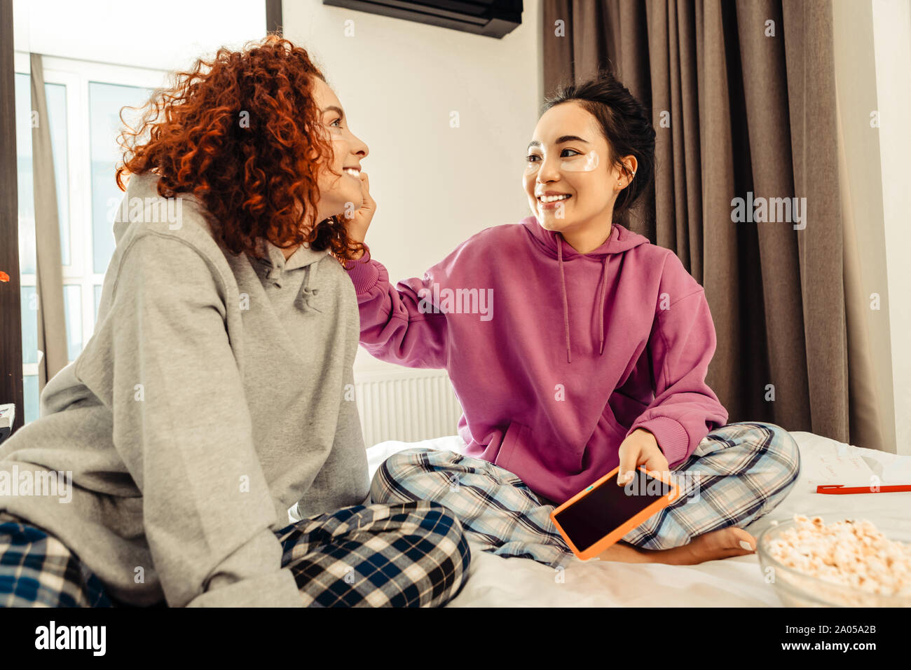 Lächelnde Mädchen auf dem Bett zu sitzen und unter den Augen von Patches Stockfoto