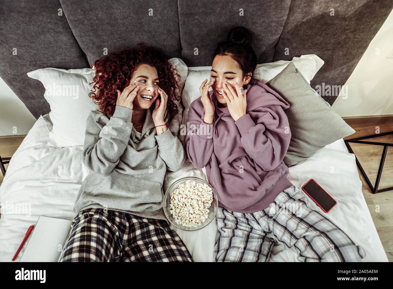 Fröhliches Mädchen mit Patches unter ihre Augen zusammen im Bett liegend Stockfoto