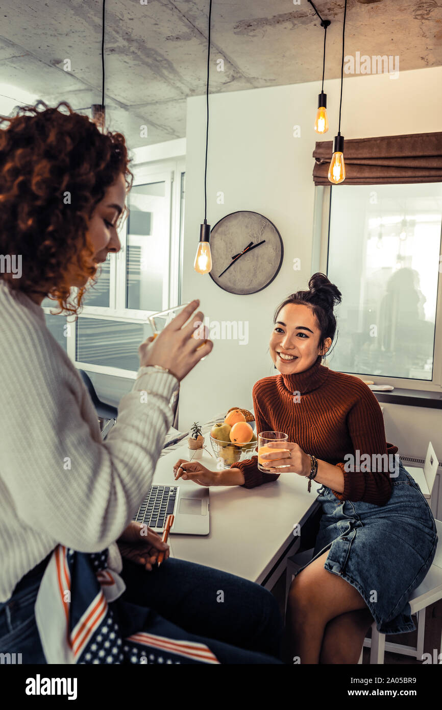 Zwei glückliche junge Frauen sitzen gemeinsam in der Küche mit einem Laptop auf dem Tisch befindet. Stockfoto
