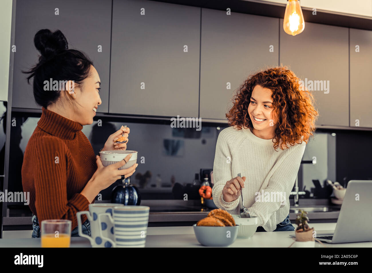 Schöne junge Frauen lächelnd und Cornflakes essen gemeinsam am Morgen Stockfoto