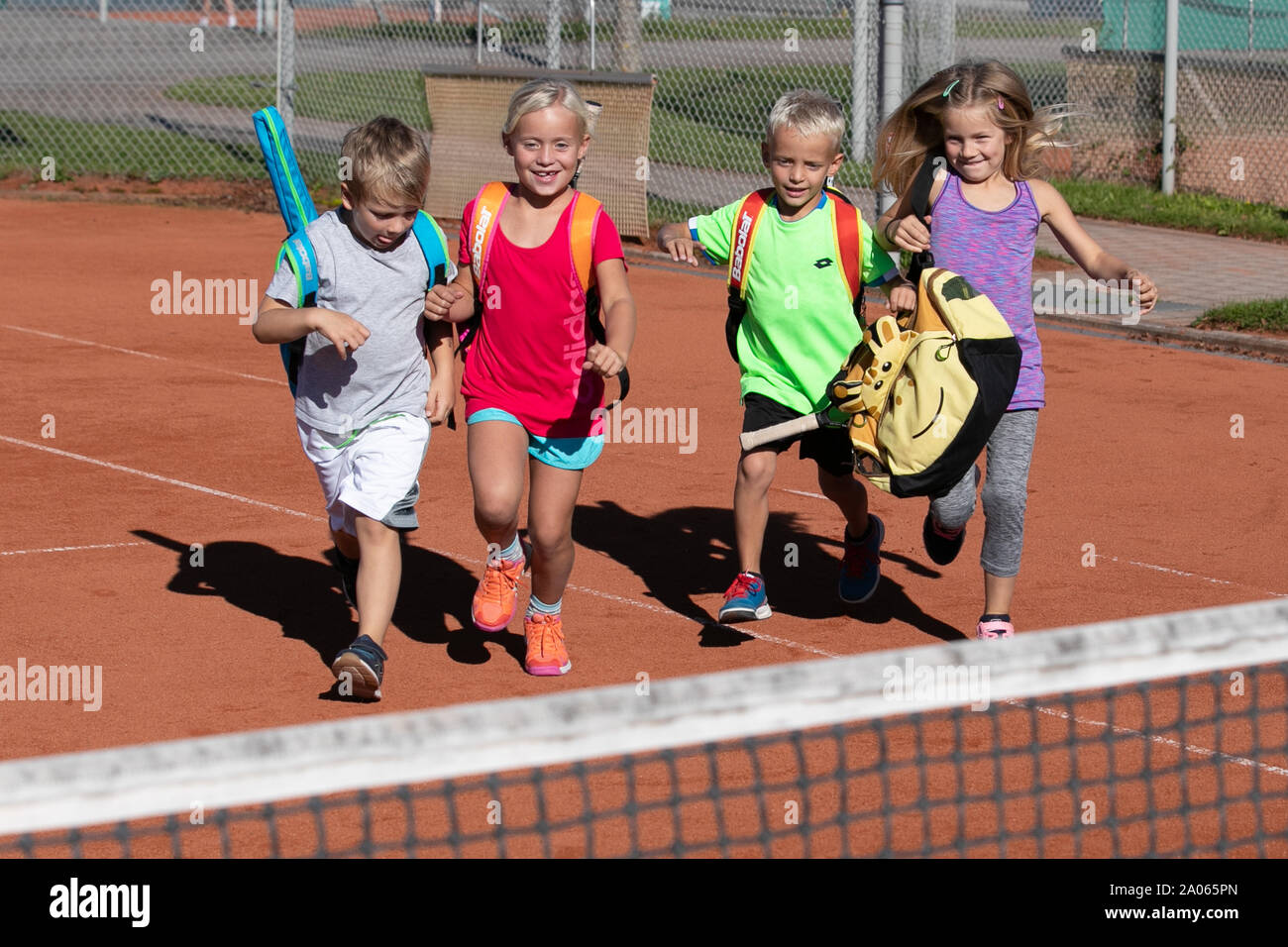 Kinder mit Taschen und rackets auf Tennisplatz Stockfoto