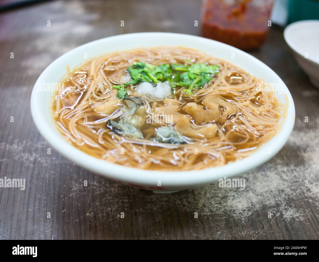 Chinesische/taiwanesische Nudelsuppe mit Austern Schweinedickdarm und Koriander in Weiß Schüssel am Restaurant Stockfoto