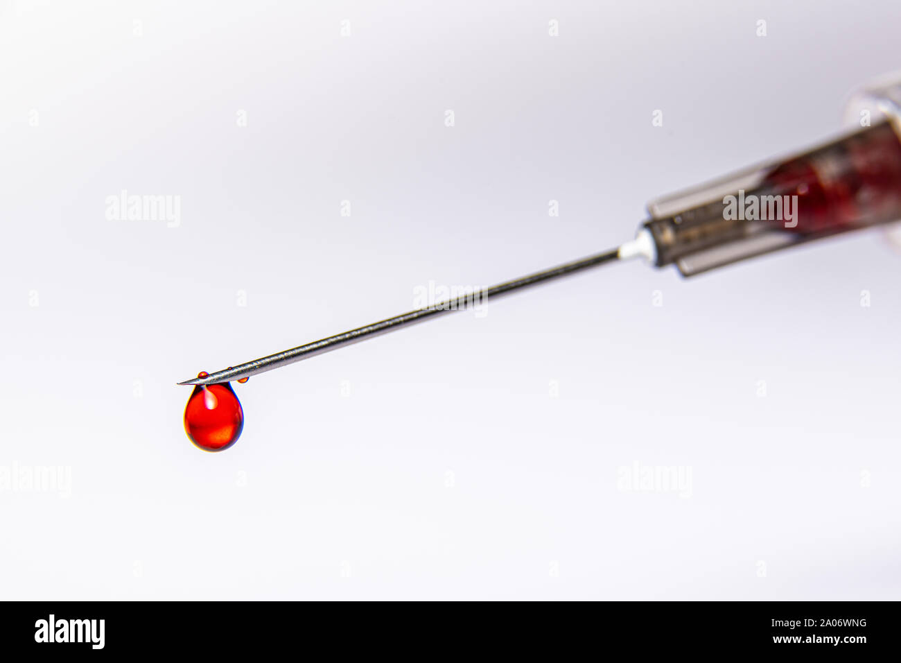 Eine Spritze tropft ein rotes Blut wie Fluid gegen eine rein weißem Hintergrund Stockfoto