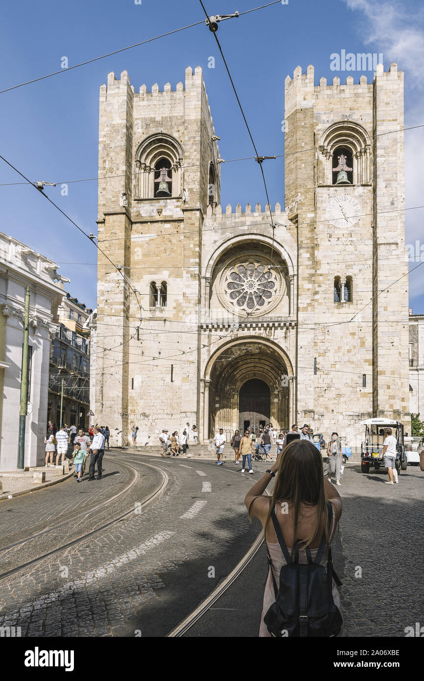 Lissabon, Portugal - August 2019: Frau, Tourist, der ein Foto von der Kathedrale mit ihrem Telefon aus der gepflasterten Straße im Stadtteil Alfama Stockfoto