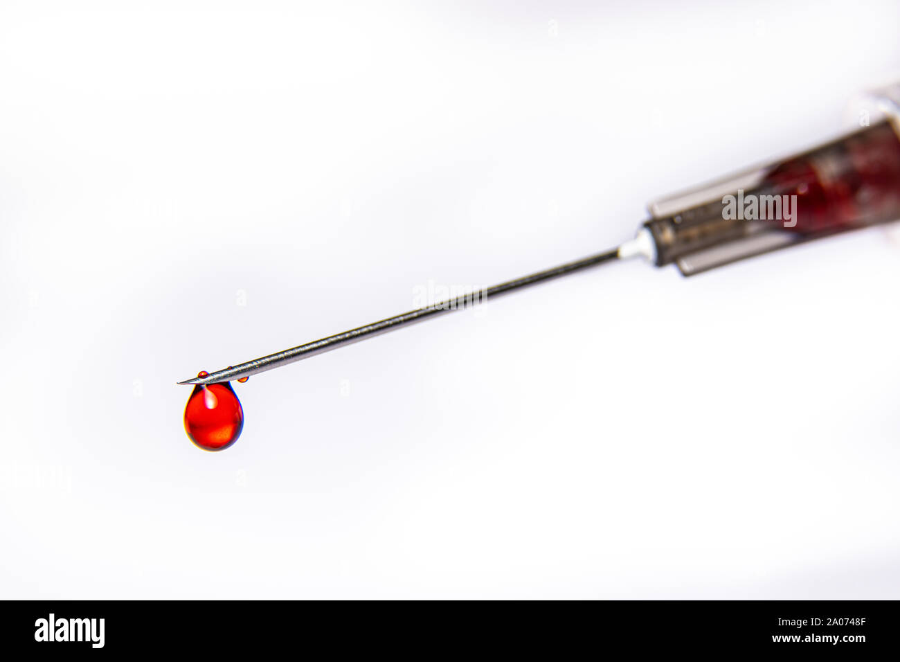 Eine Spritze tropft ein rotes Blut wie Fluid gegen eine rein weißem Hintergrund Stockfoto