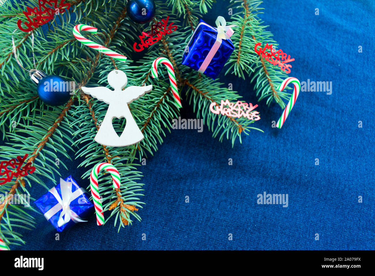 Weihnachten Hintergrund in blau mit einem Weihnachtsbaum Zweig mit Geschenkboxen, Glocken, Süßigkeiten und ein weißer Engel Abbildung eingerichtet. Kopieren Sie Platz. Stockfoto