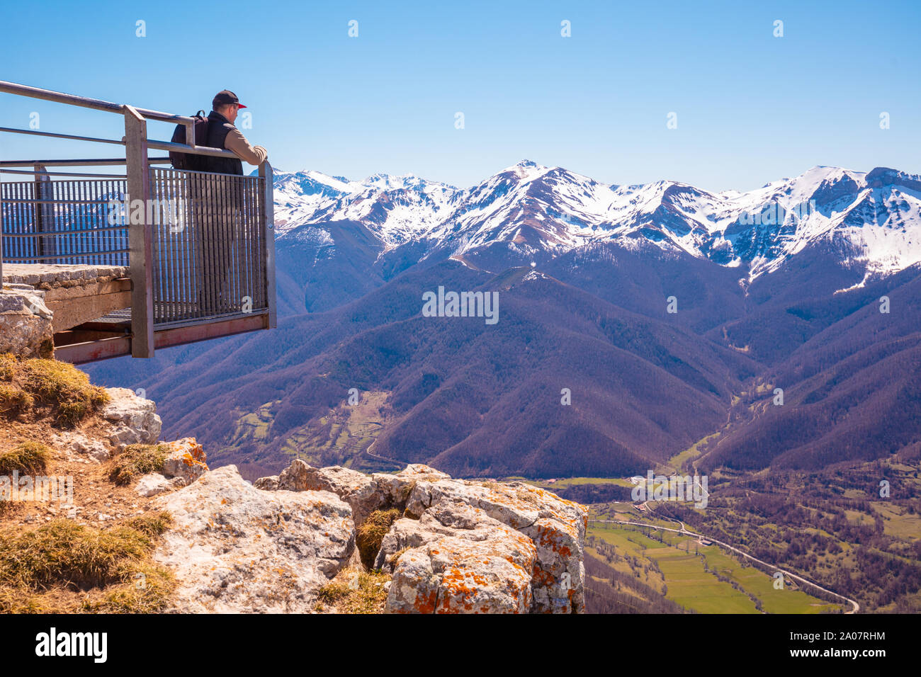 Ein Mann touristische steht auf einem Aussichtspunkt über das Tal gegen Berge bedeckt mit dem Schnee. Ein Mann sieht einen schönen Panoramablick auf die Berge. Nati Stockfoto