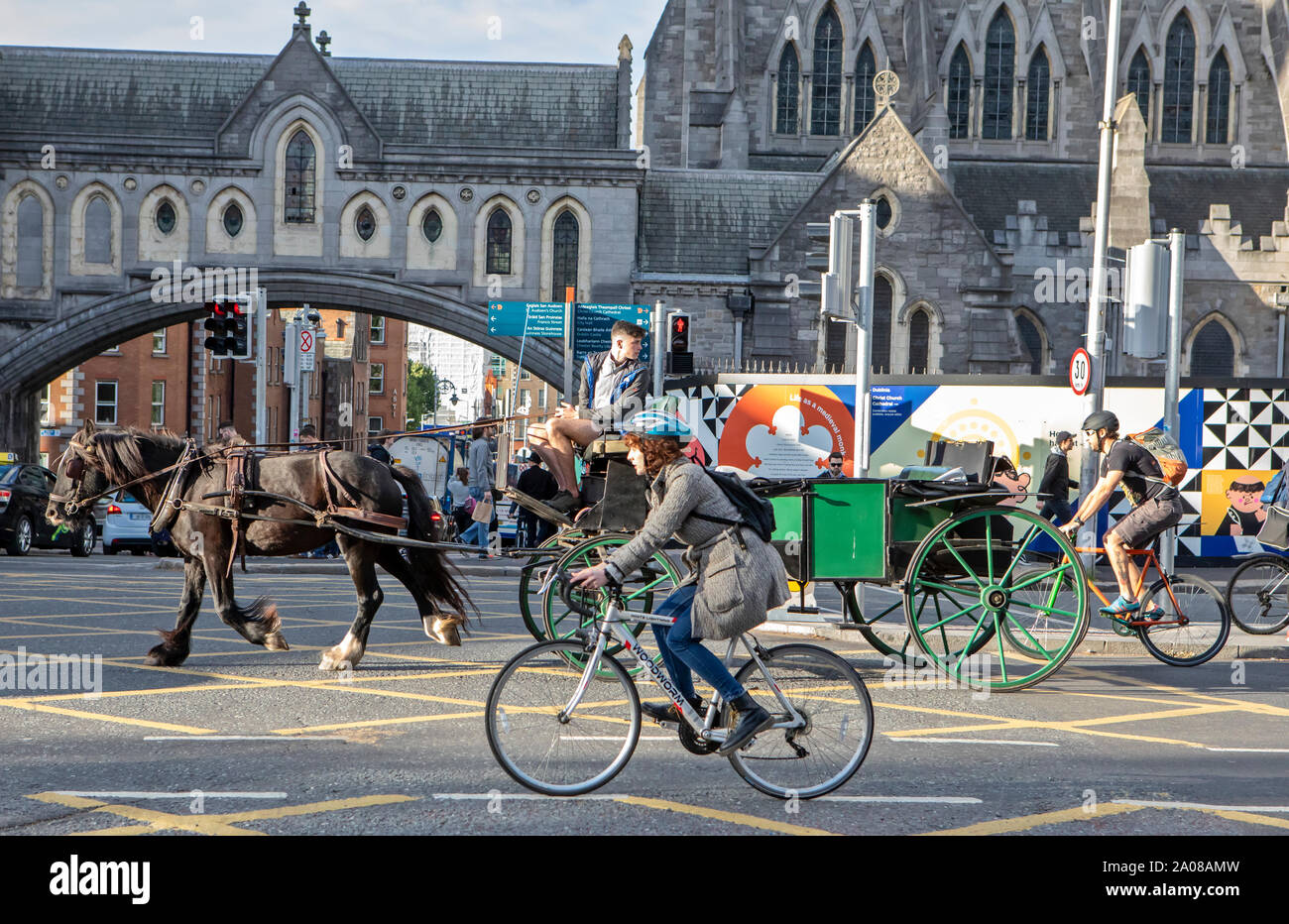 Fahrradfahrer, ein Pferdewagen, Autos und Fußgänger teilen sich die Straße in Dublin, Irland. Stockfoto