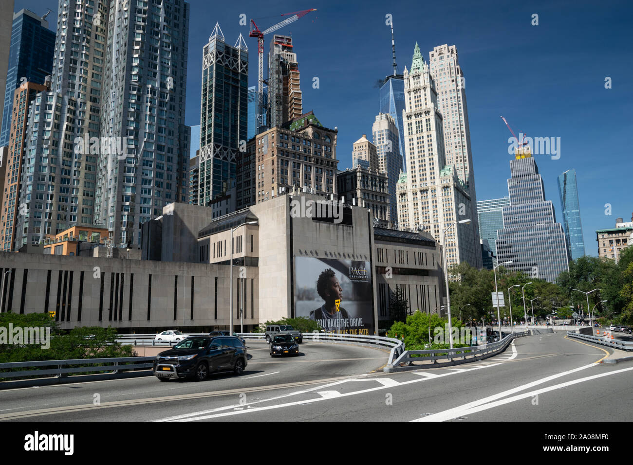 Im Vordergrund sieht man sterben Straße, sterben Über die Brooklyn Bridge führt. Dahinter befindet sich die Pace Universität mit Werbeplakat. Das ganze vor de Stockfoto