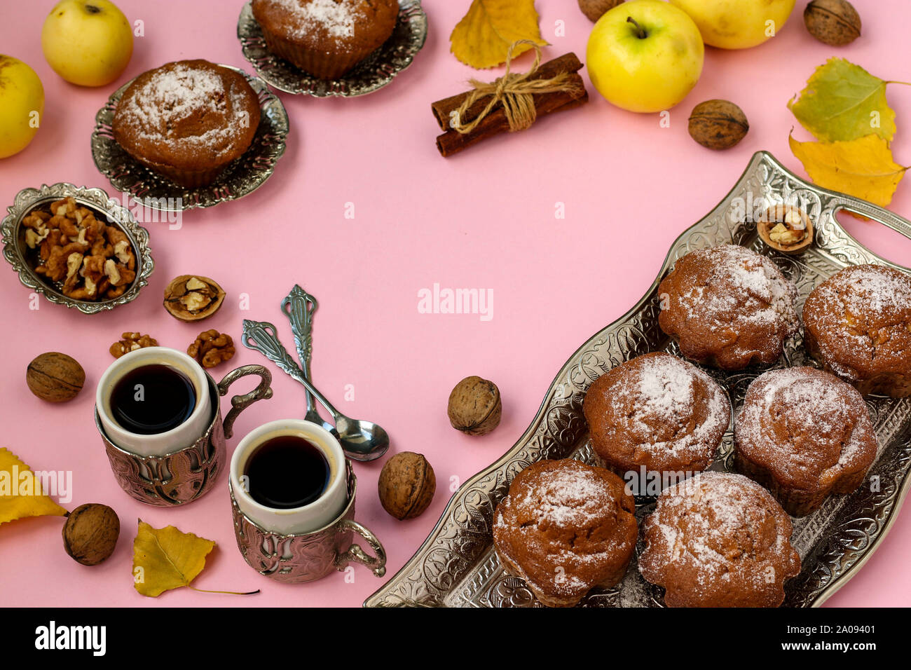 Hausgemachte Muffins mit Äpfel und Nüsse und zwei Tassen Kaffee auf einem rosa Hintergrund angeordnet, Ansicht von oben, Kopieren, Herbst Komposition, horizontal Stockfoto