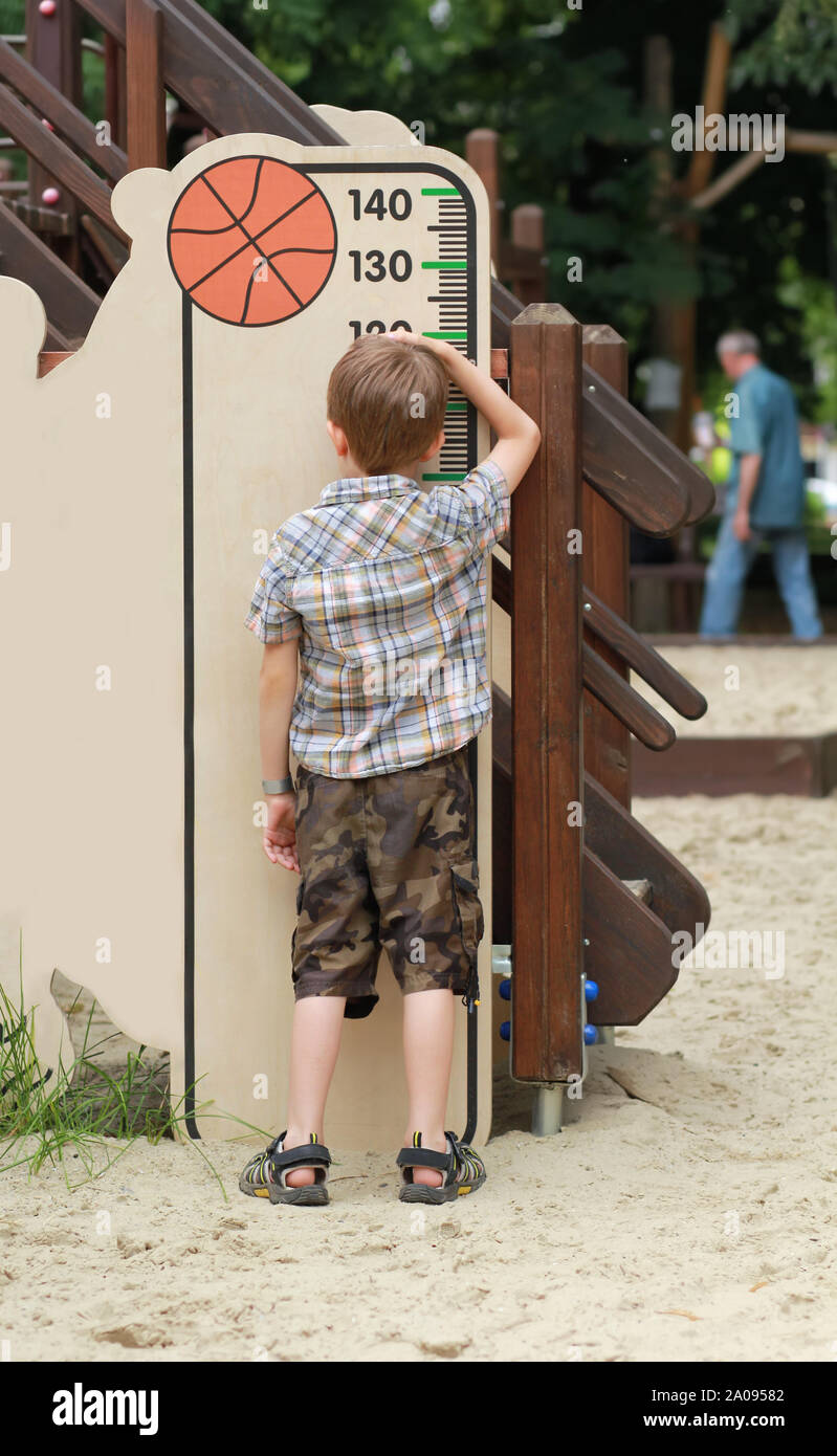 Fünf Jahre alten Jungen seine Höhe Messen auf dem Kinderspielplatz Stockfoto