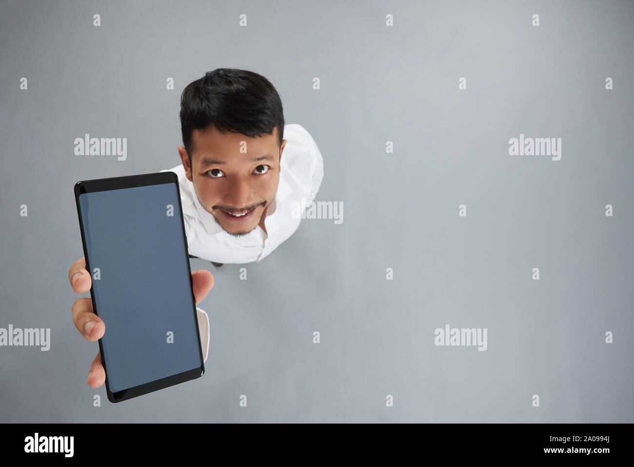 In lächelnden Mann Hand über der Ansicht von oben auf der grauen Studiohintergrund Smartphone Stockfoto