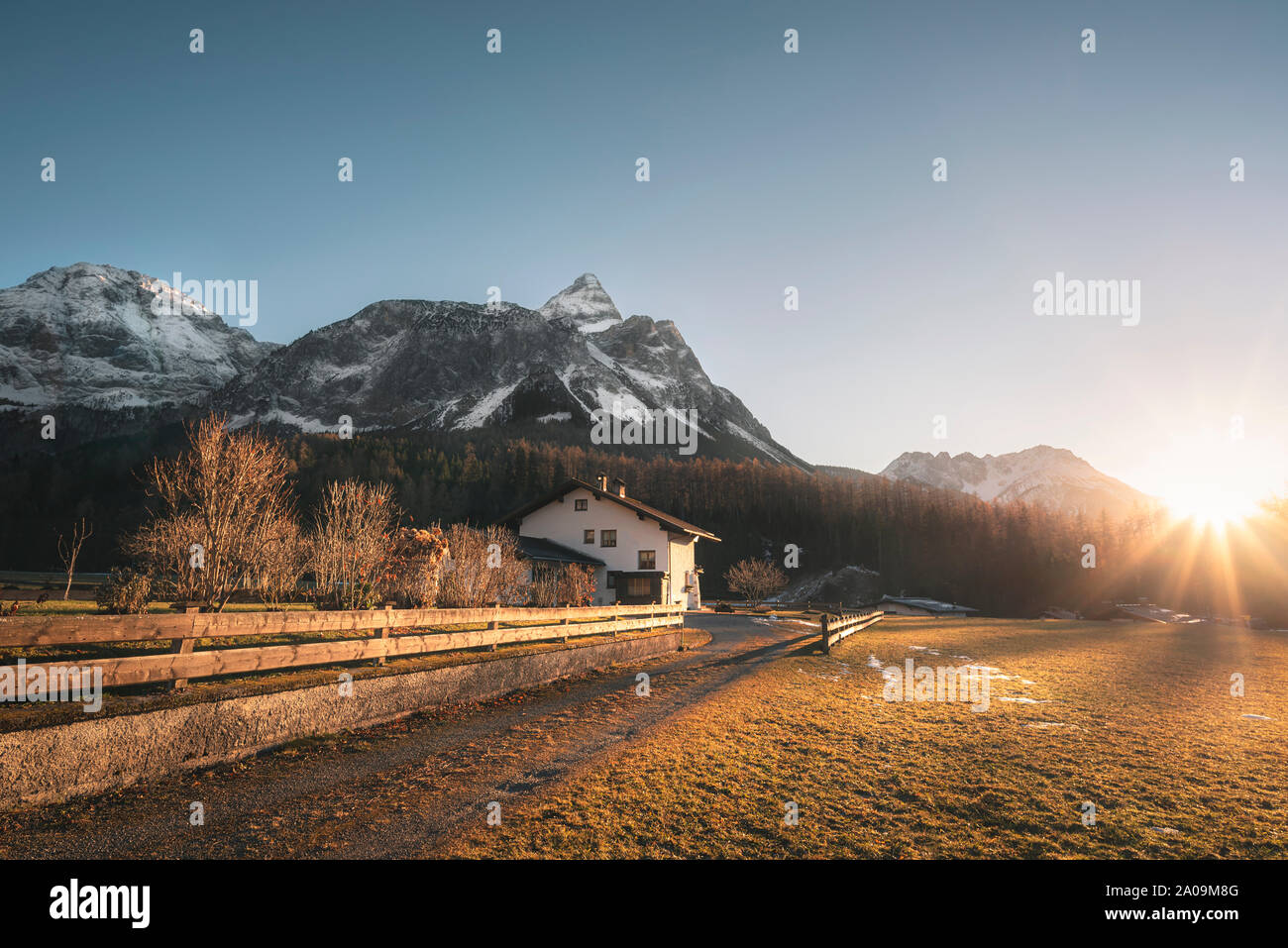 Schneebedeckten Alpen berge Gipfel und Österreichischen Bauernhof im Abendlicht, an einem sonnigen Tag des Winters, in Ehrwald, Österreich. Dezember Sonnenuntergang Landschaft. Stockfoto