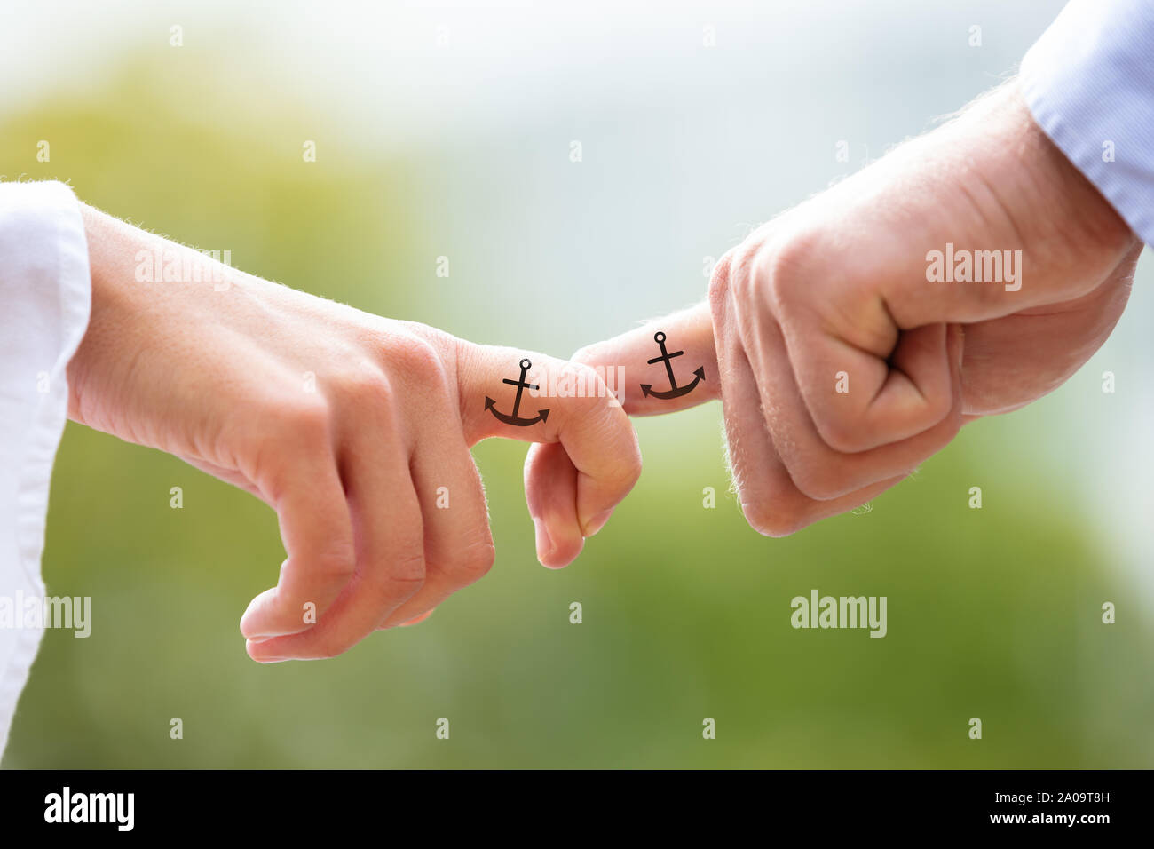 Liebende Paar hält jedes anderen Finger mit schwarzem Anker Zeichen Tattoo  gegen verschwommenen Hintergrund Stockfotografie - Alamy