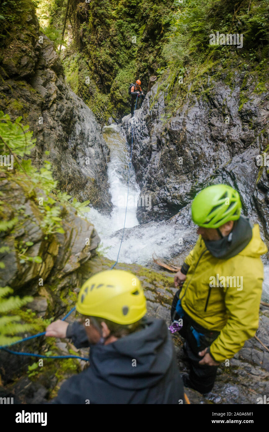 Drei Männer ein, um eine Linie zu sichern und sicher ein Slot Canyon cross beheben. Stockfoto