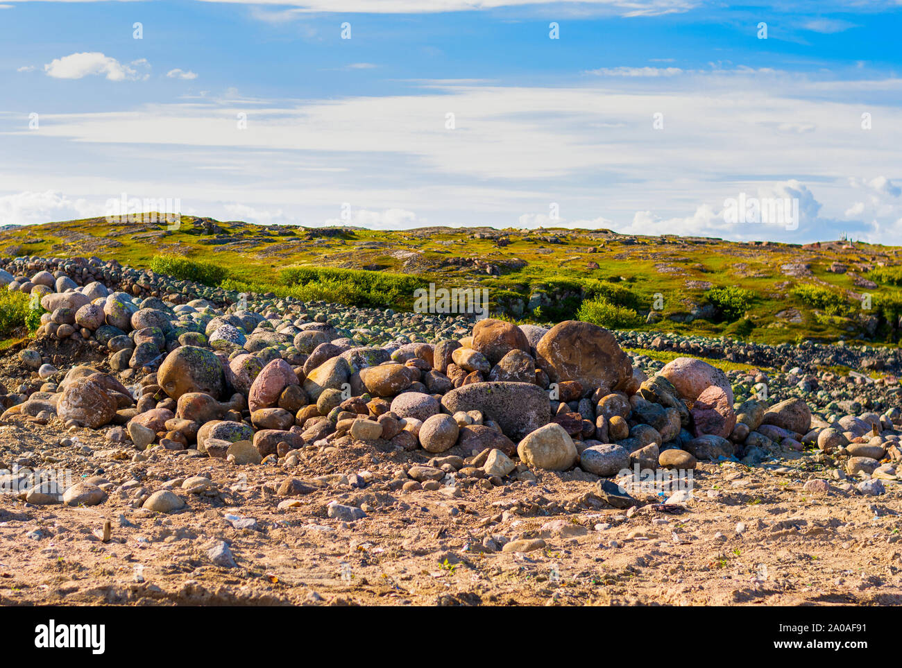 Eine Handvoll von riesigen Steinen von Gras umgeben. Hellen Himmel in den Wolken. Hügeln im Hintergrund. Stockfoto