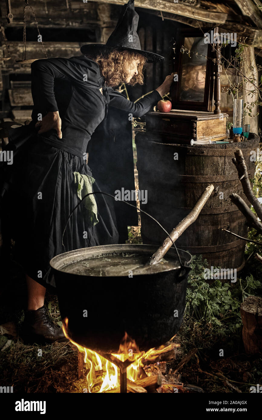 Alte Hexe brauen tödlichen Trank für Halloween in einen gusseisernen Topf Stockfoto