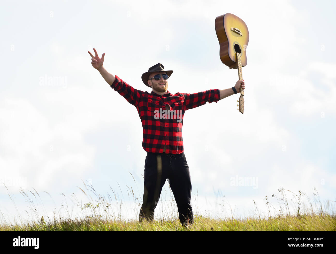 Inspiriert land Musiker. United mit der Natur. Stattlicher Mann mit Gitarre. Country Music Konzept. Gitarrist Land Sänger stand im Feld Himmel Hintergrund. Landhausstil. Sommer Urlaub. Wandern Song. Stockfoto