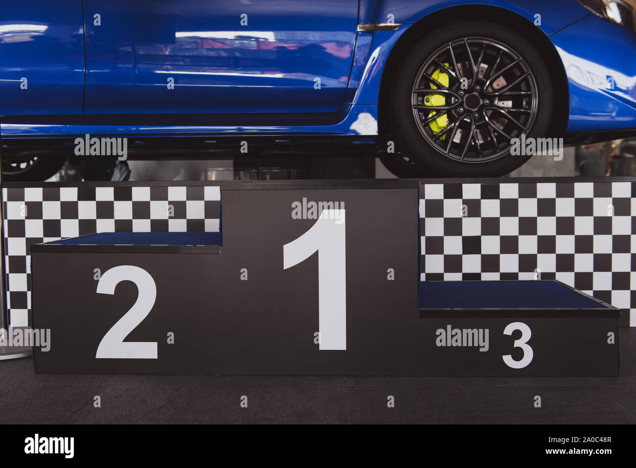 Leistungsstarke blaue Sport Auto hinter dem Podest. Rallye Sockel mit der ersten, zweiten und dritten Platz. Preisverleihung nach dem Wettbewerb. Der Hauptpreis Stockfoto