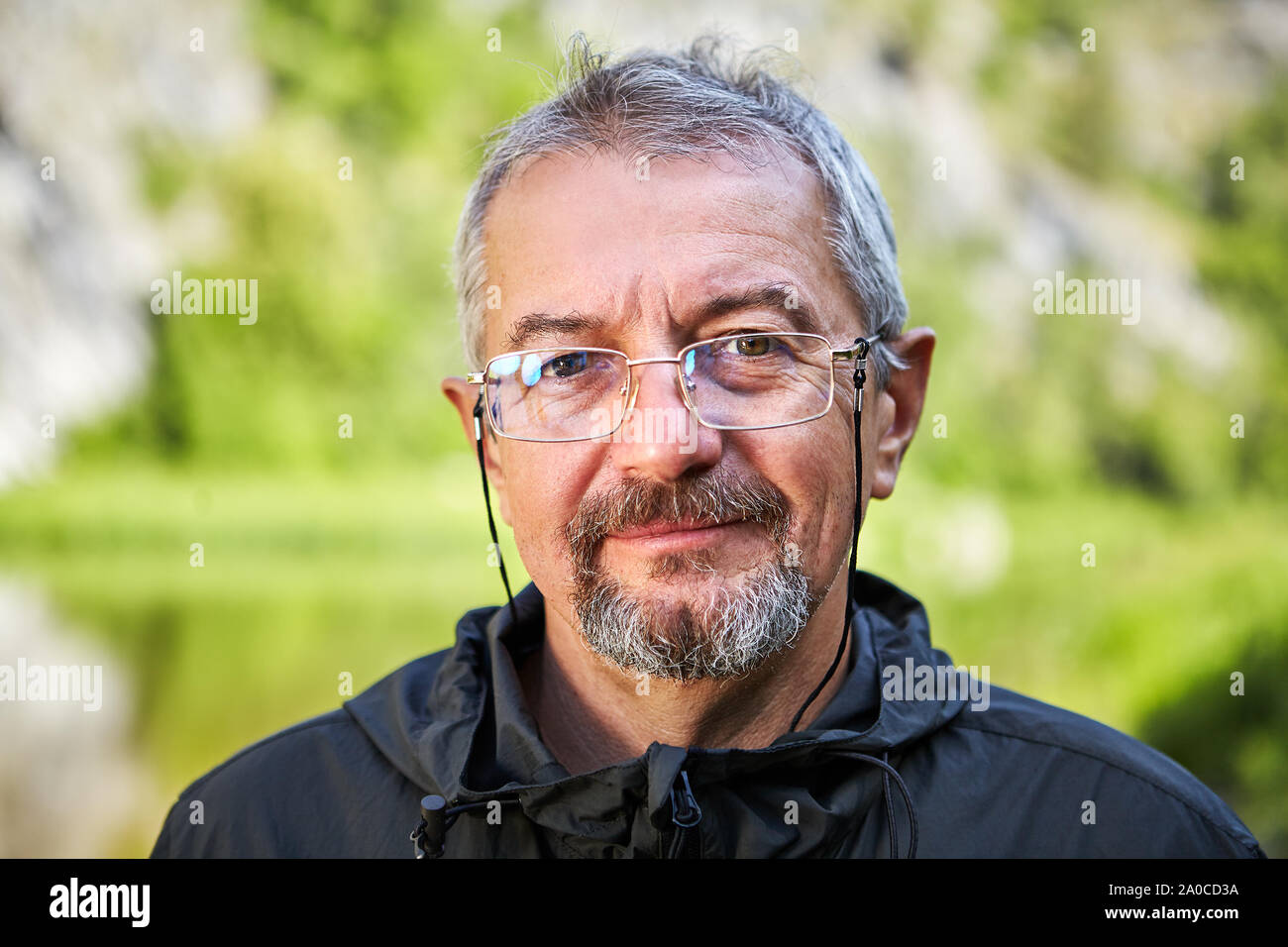 Close up Portrait eines älteren intelligenter Mann in Gläsern und mit einem grauen Bart. Lächelnde Gesicht eines gebildeten Menschen im Rentenalter. Outdoor Portrait Stockfoto