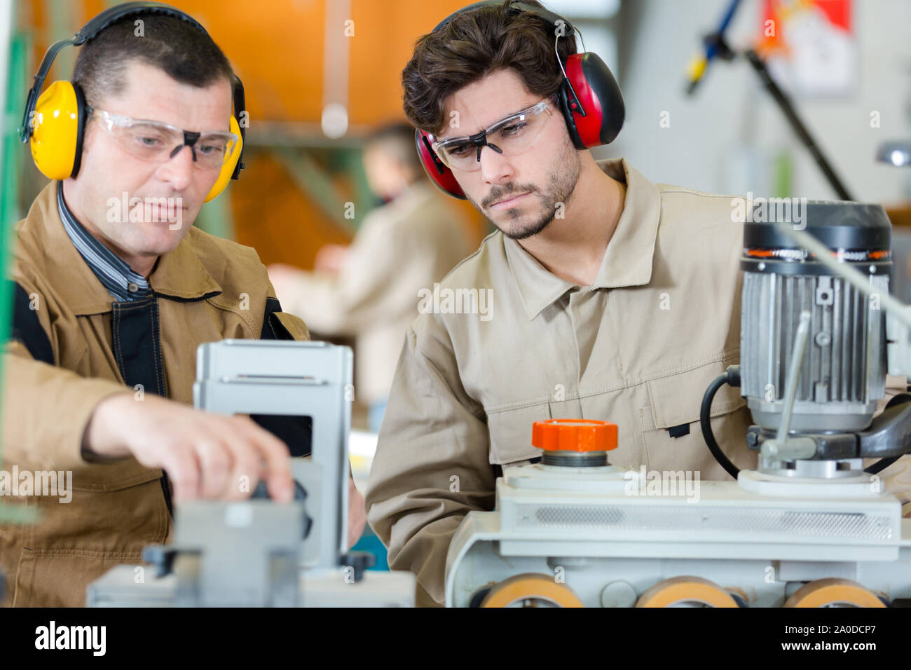 Arbeitnehmer mit Ohrenschützer und Schutzbrille Fummeln eine Maschine Stockfoto