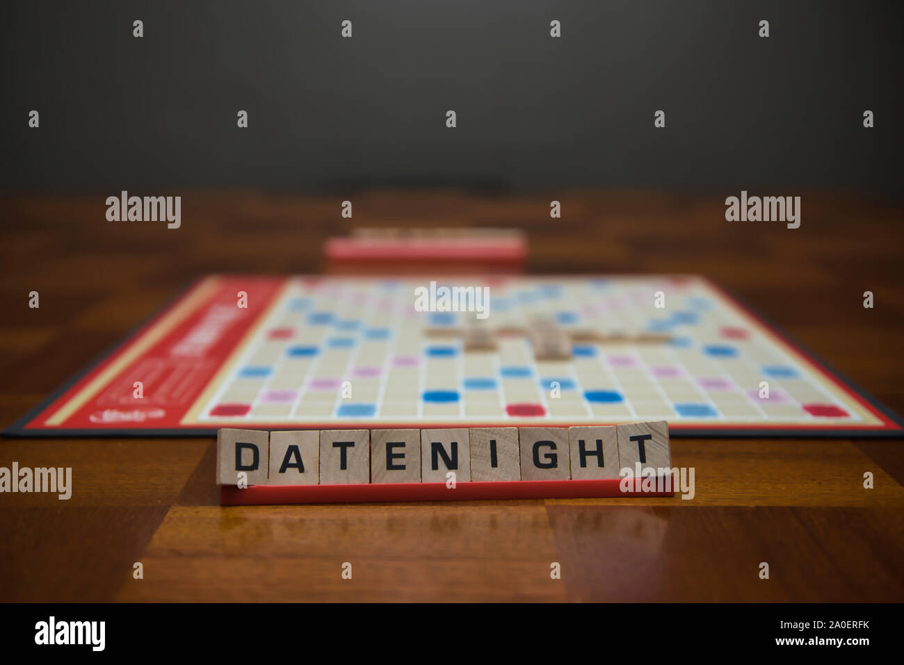Brief Fliesen Buchstabieren der Wörter Datum Nacht auf stehen im Vordergrund mit unscharf Spielbrett im Hintergrund. Stockfoto
