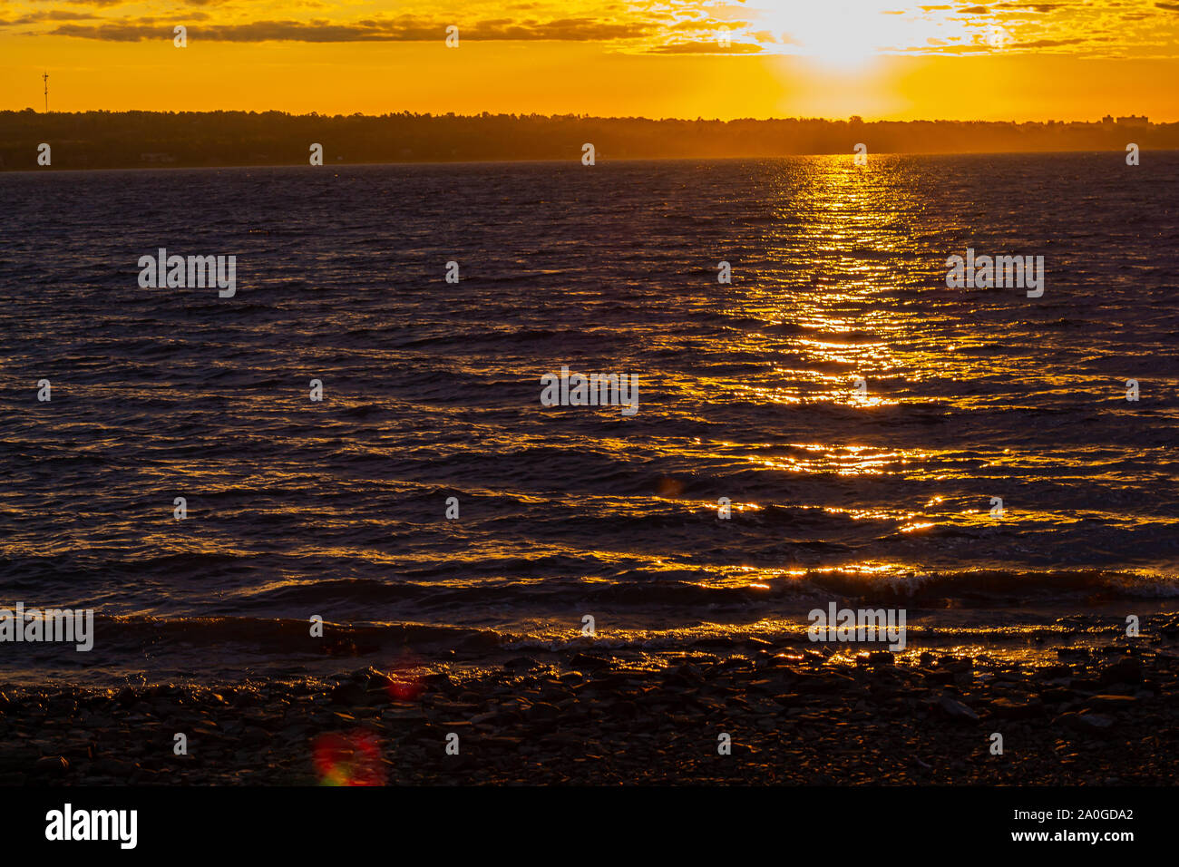 Die Sonne über einer reflektierenden Fluss, lebendige und brillante orange Farbe. Stockfoto
