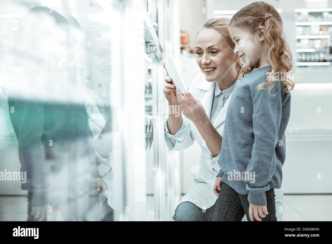 Kleine Mädchen und ein Apotheker lächelnd an einer Tablette. Stockfoto