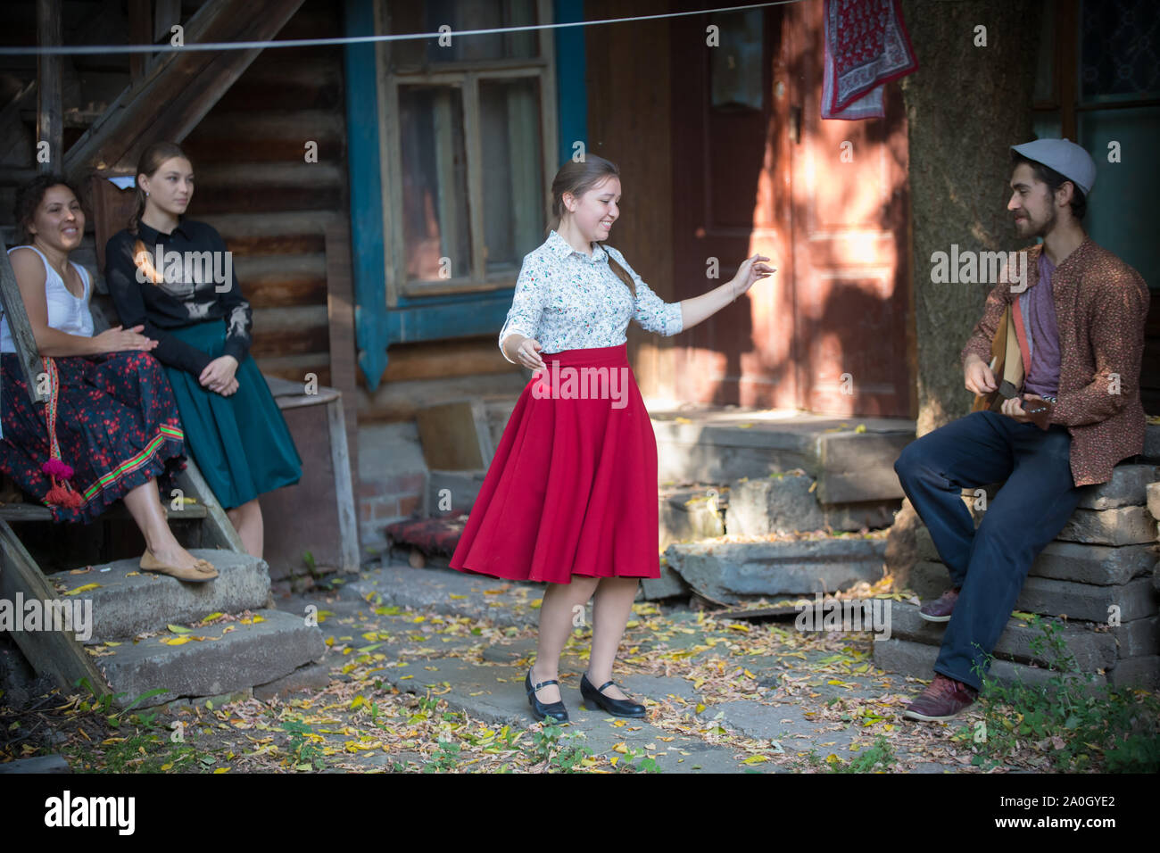 Eine Frau Tanz von der Musik in der Nähe des Country House - ein Mann spielt Balalaika Stockfoto