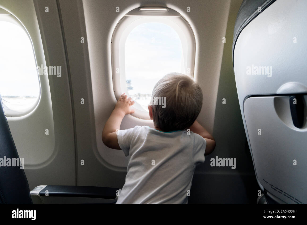 Ein Jahr alten baby boy Neugierig durch das Flugzeug Fenster Stockfoto