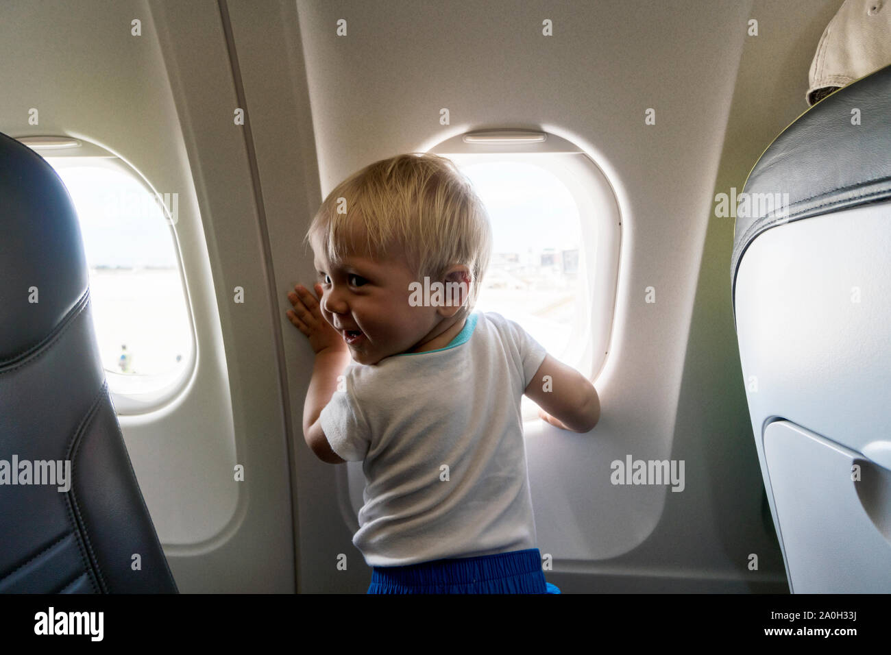Glücklich und aufgeregt, ein Jahr alten baby boy neugierig durch das Flugzeug Fenster suchen Stockfoto