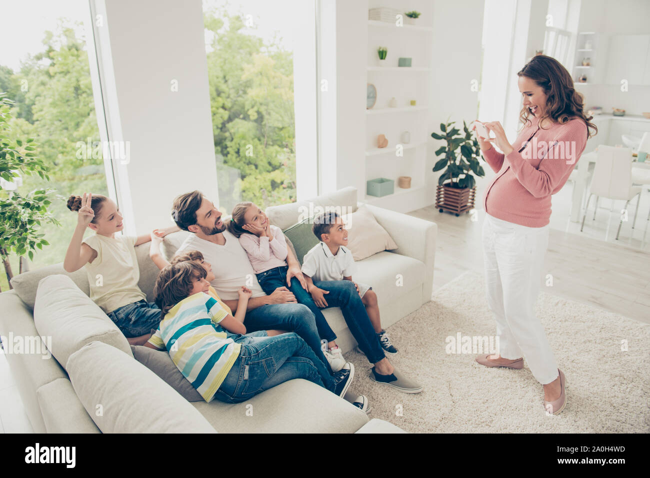 Big bezaubernd schöne fröhliche Pflegefamilie, fünf Kinder, afro Brüder und Schwestern sitzen auf Diwan mit Adoptivvater, schwangere Mutter pho machen Stockfoto