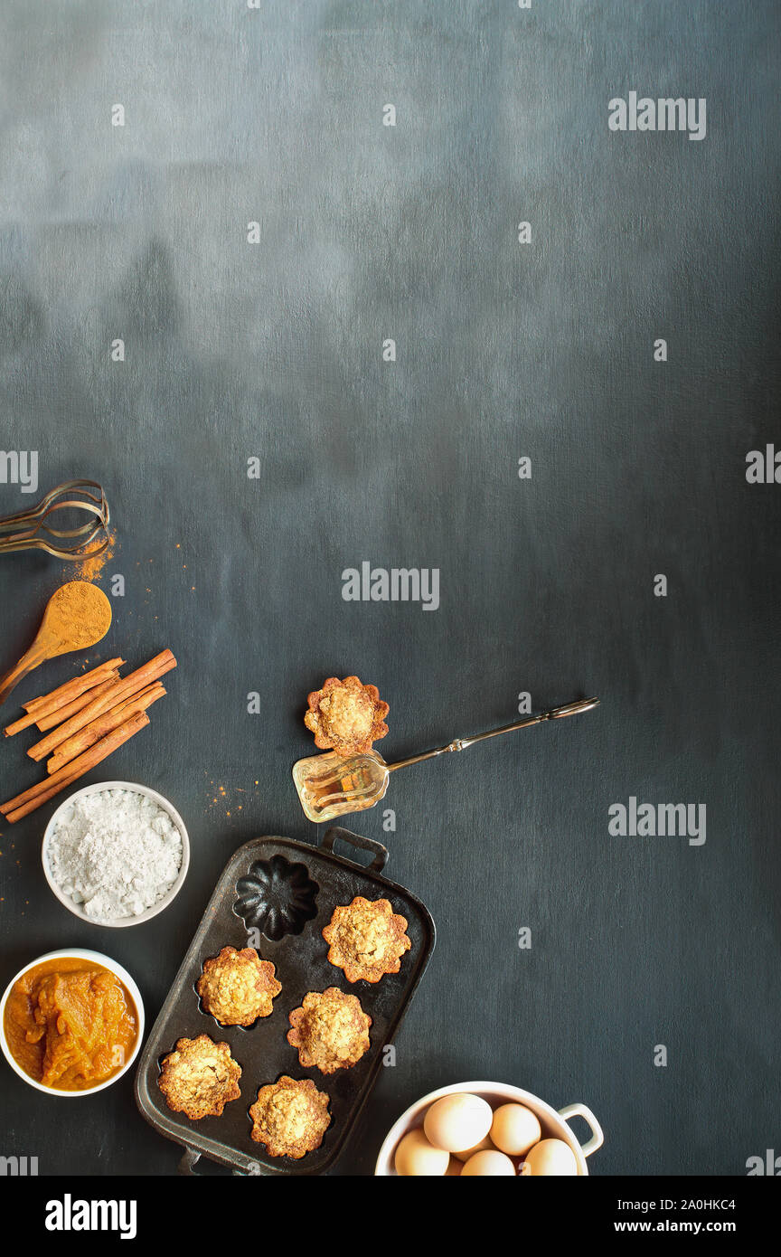 Schöne frische hausgemachte Kürbis Muffins mit kürbispüree, Mehl, Zimt und braune Eier auf dunklem Hintergrund. Bild geschossen von der Ansicht von oben. Stockfoto