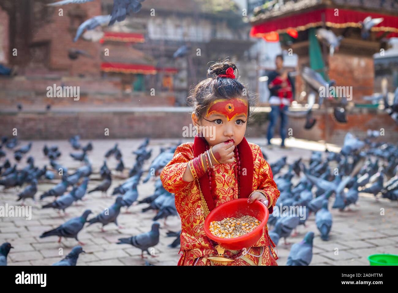 Kleines Mädchen gekleidet als Kumari Gott die Fütterung der Tauben im Kathmandu Durbar Square während Indra Jatra Festival Stockfoto