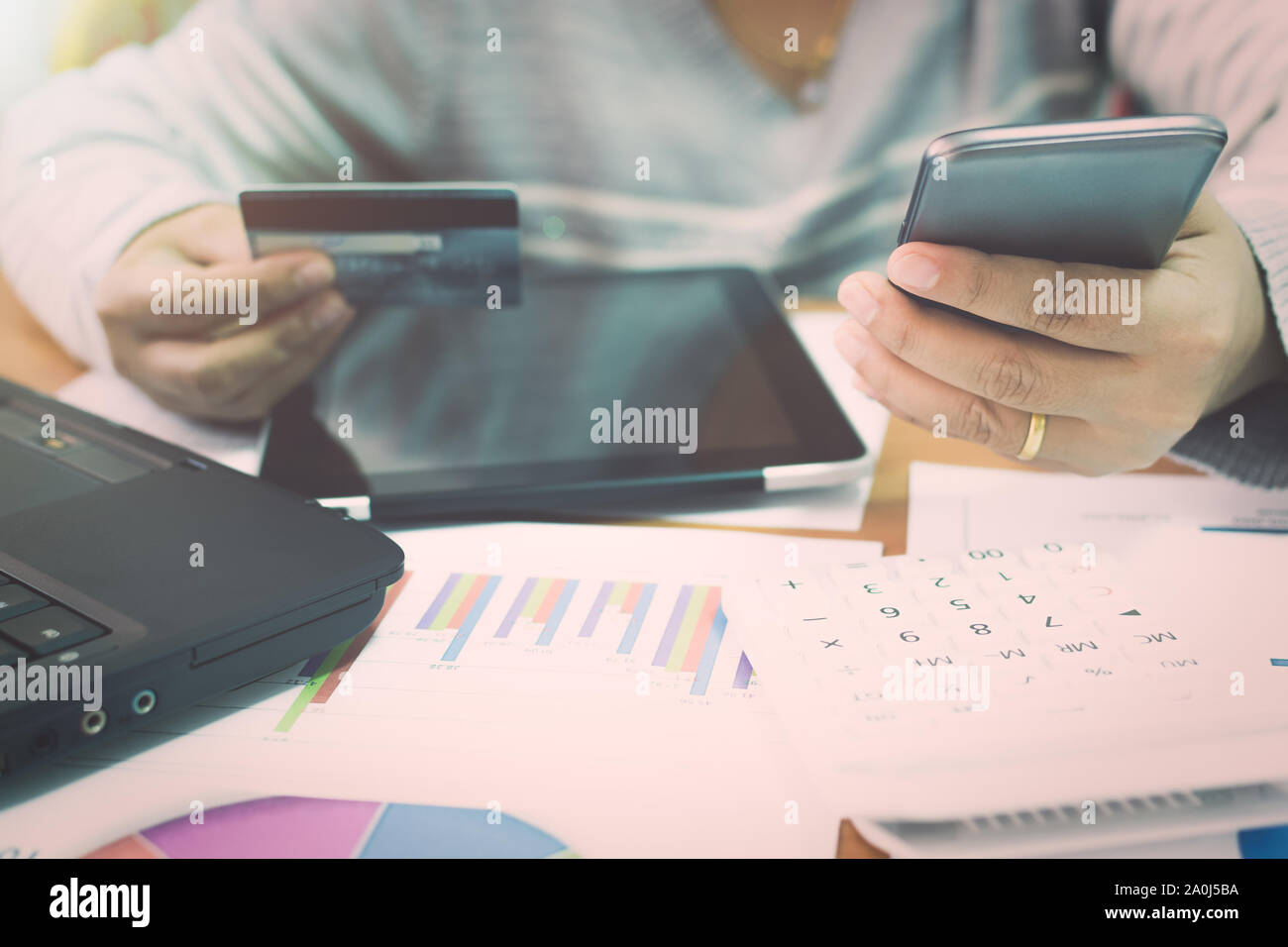 Geschäftsfrau mit Handy Zahlung per Kreditkarte mit Marketing Informationen graph im Büro online. Stockfoto