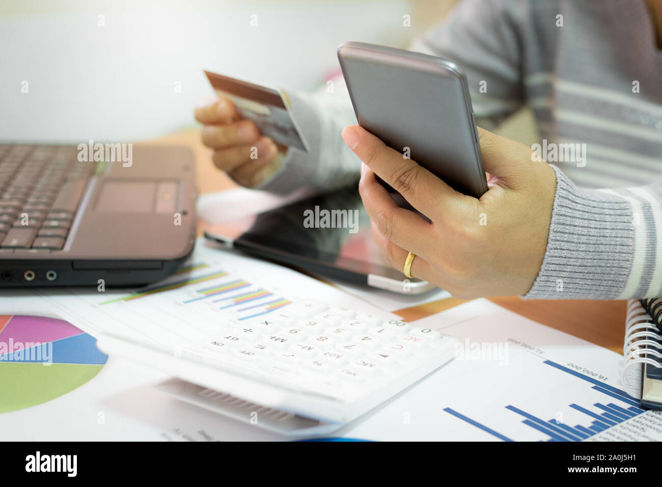 Geschäftsfrau mit Handy Zahlung per Kreditkarte mit Marketing Informationen graph im Büro online. Stockfoto