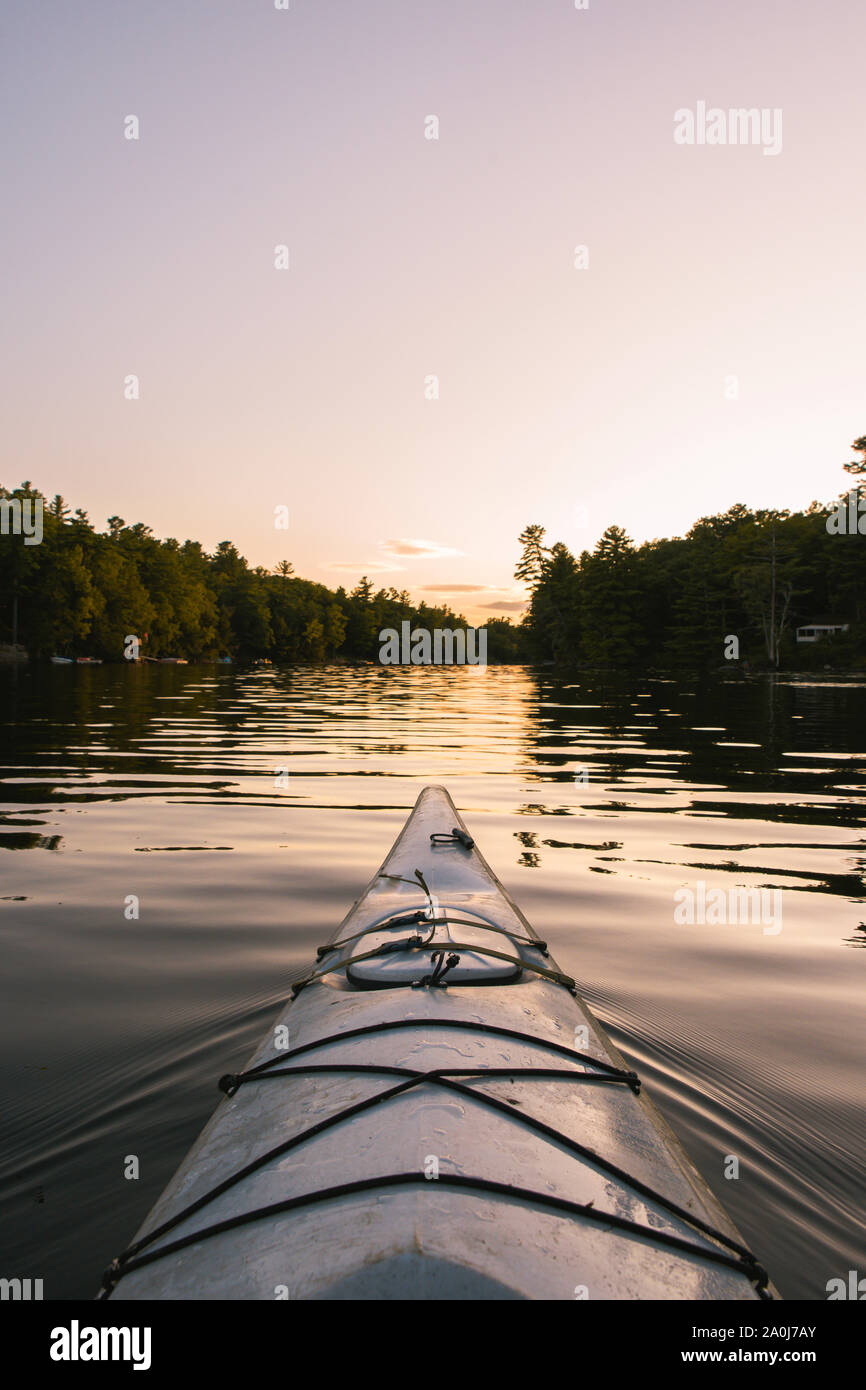 Kajakfahren auf dem ruhigen Wasser bei Sonnenuntergang von der Sicht der Paddler. Stockfoto