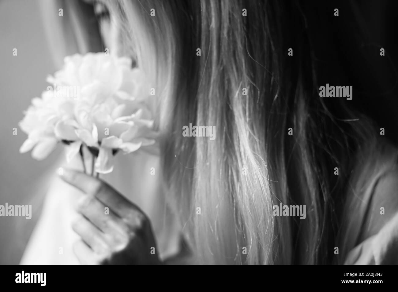 Verschwommene Portrait eines jungen Mädchens sniffing Blumen in den Händen, weibliche Träume und Vergnügen. Schwarz und Weiß Foto Stockfoto