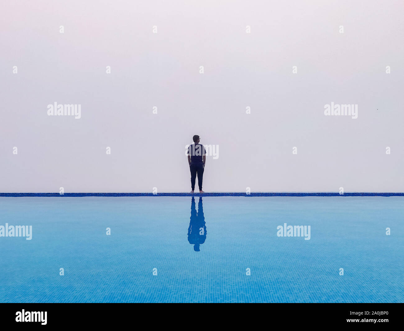 Ein Kerl, der an der Kante der Infinity-pool mit weißem Schleier Stockfoto