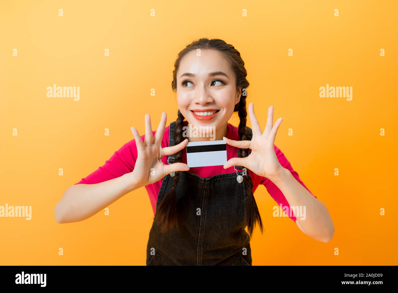 Junge lächelnde schöne asiatische Frau mit Kreditkarte in der Hand zeigen, Vertrauen und Zuversicht für eine Zahlung. Stockfoto
