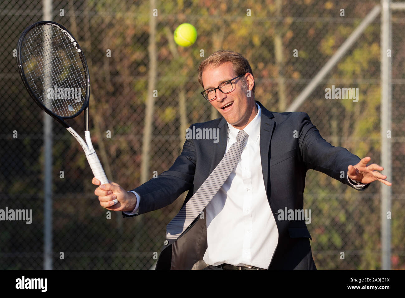 Unternehmer im dunklen Anzug Tennis spielen Stockfoto