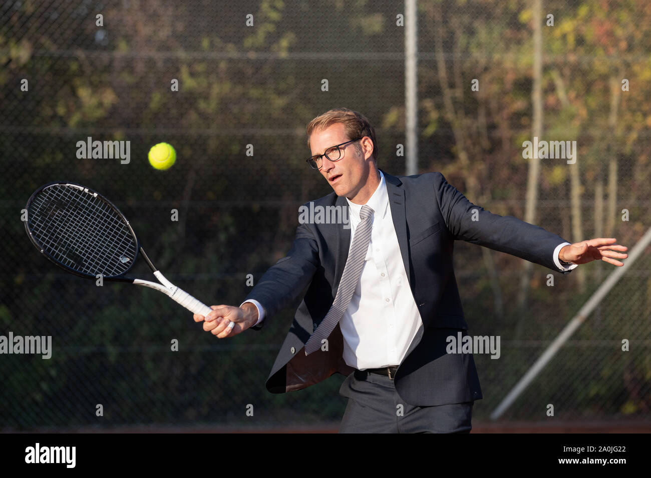 Unternehmer im dunklen Anzug Tennis spielen Stockfoto