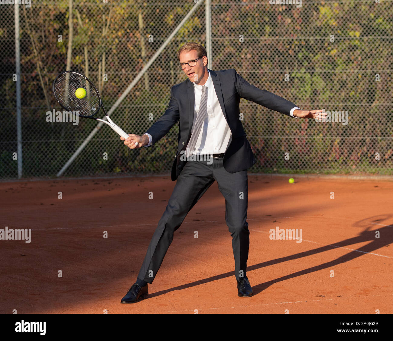Lächelnd Geschäftsmann in dunklen Anzug Tennis spielen Stockfoto