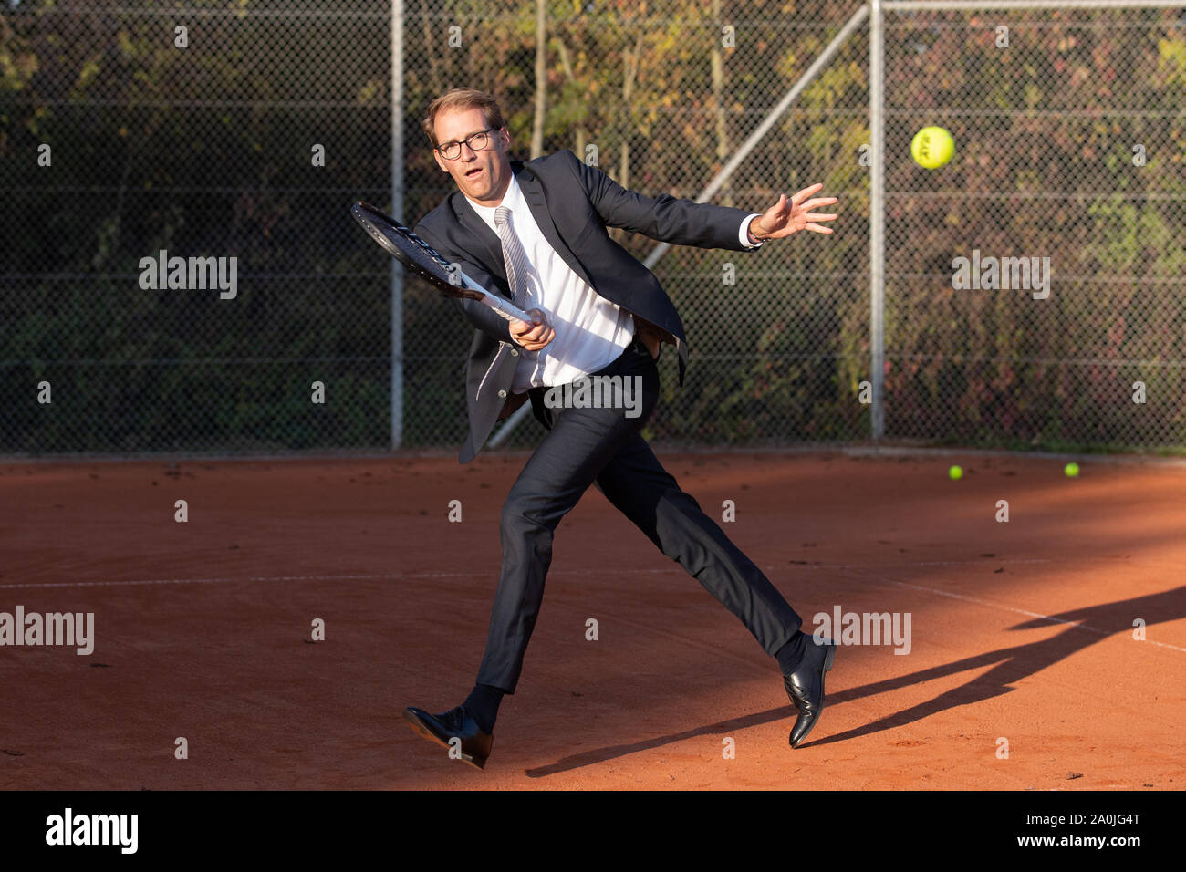 Unternehmer im dunklen Anzug Tennis spielen Stockfoto