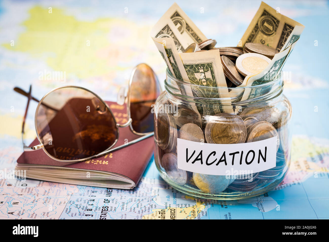 Urlaub Haushalt Konzept. Urlaub Geld zu sparen, in einem Glas mit Reisepass und Sonnenbrille auf Weltkarte Stockfoto