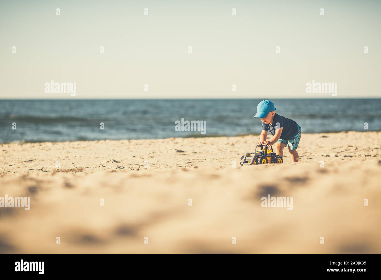 Toddler Boy mit Spielzeug spielen an einem sonnigen Strand. Kleines Kind gehen auf Sand. Schöne inspirierende Strand und Blick aufs Meer, Landschaft. Stockfoto