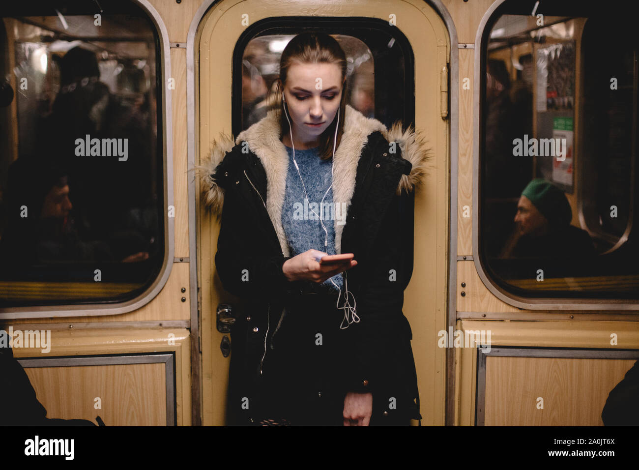 Junge Frau hört Musik auf das Telefon während der Fahrt in der U-Bahn Stockfoto