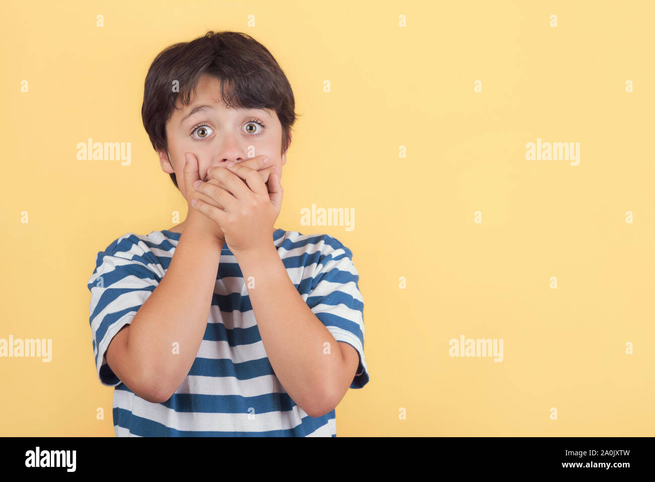 Kinder, die ihren Mund mit der Hand auf gelbem Hintergrund Stockfoto