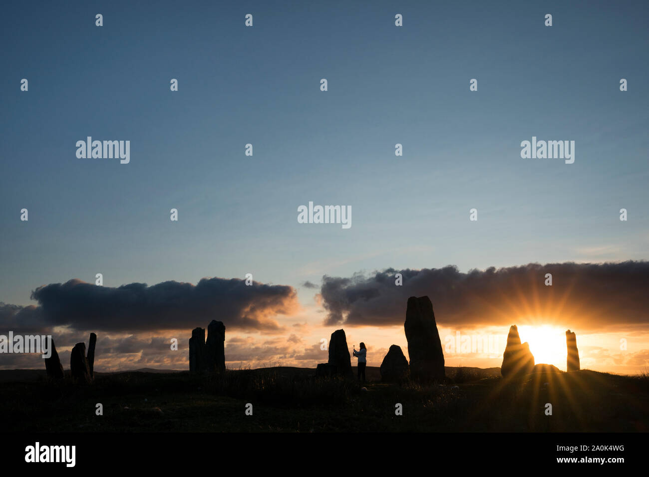 Touristische videos besuchen Sie sie bei Sonnenuntergang an den Callanish Standing Stones III vor blauem Himmel auf der Insel Lewis, Äußere Hebriden, silhouetted Scotl Stockfoto